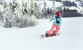 Woman in ski suit looks over her shoulder going down the hill on